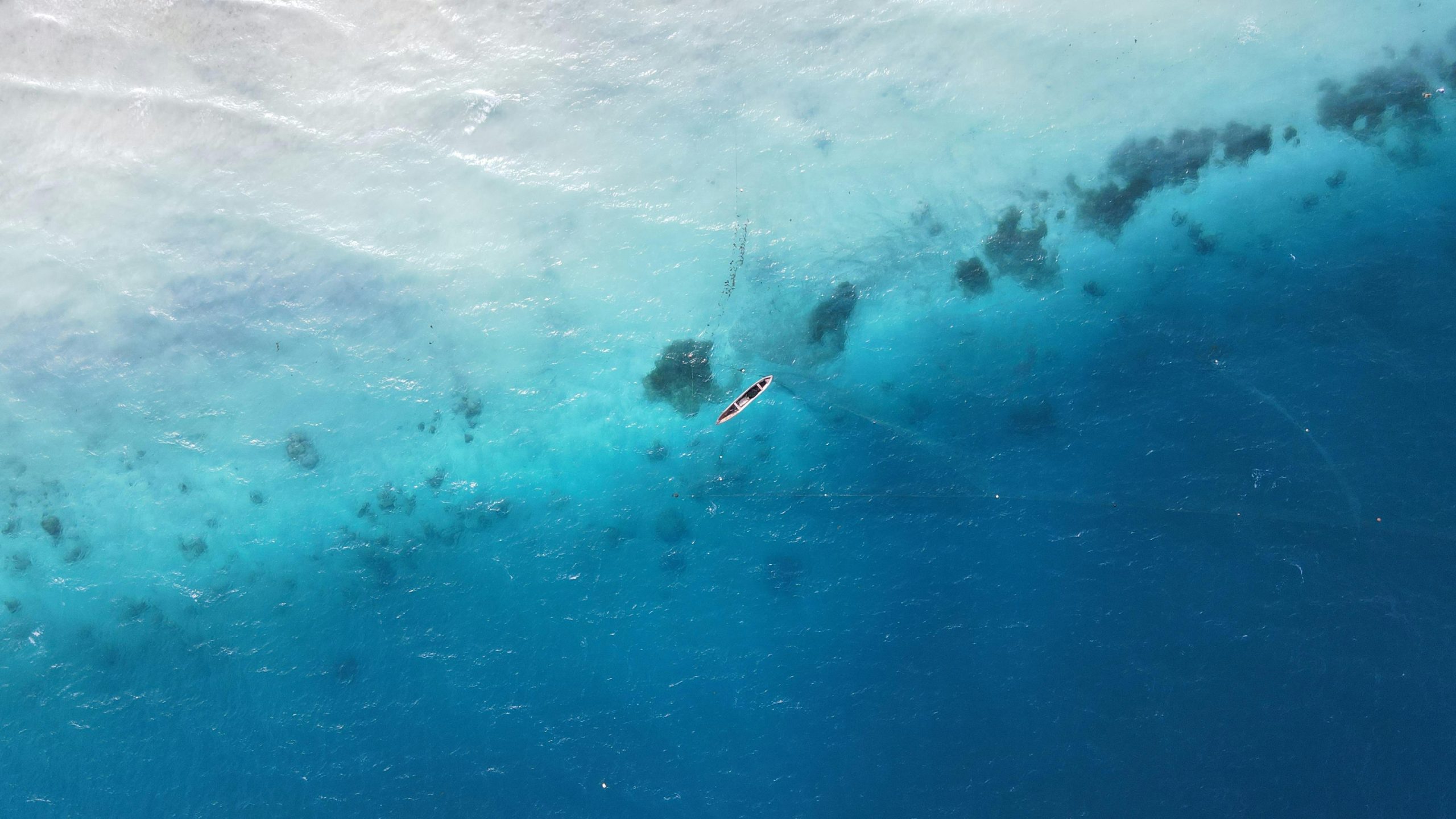 Drone shot of a lone boat in the vibrant blue waters off the coast of Zanzibar, Tanzania.
